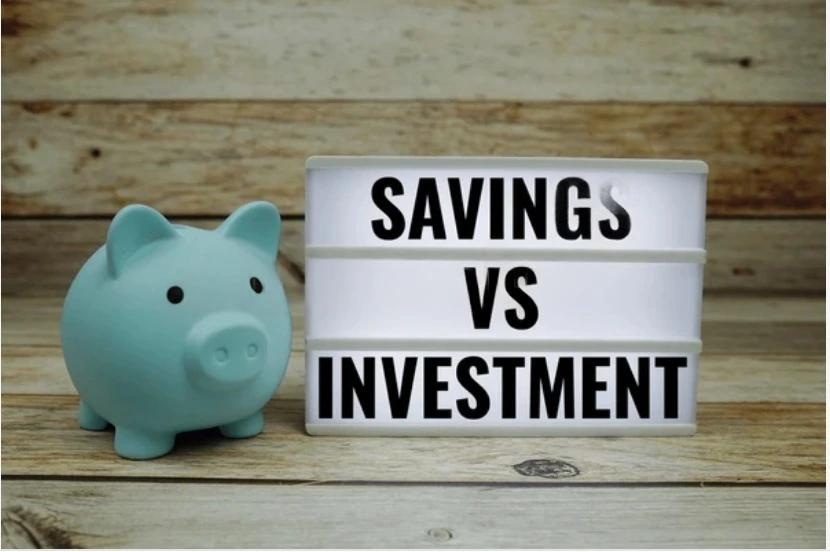 “Savings vs Investing concept image with piggy bank and comparison sign — representing the difference between saving money and investing for financial growth.”